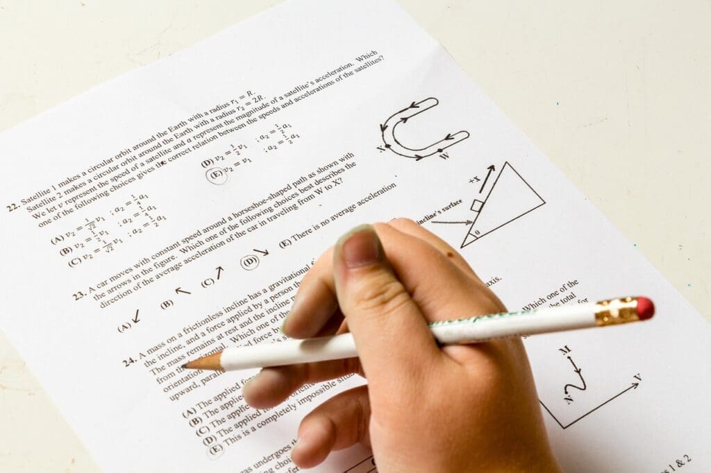 Hand holding pencil above exam paper